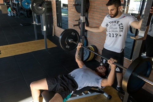 Person lifting weights with a spotter. 