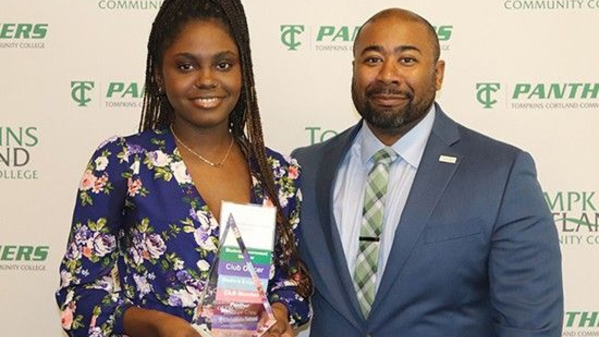 student holding award standing next to administrator