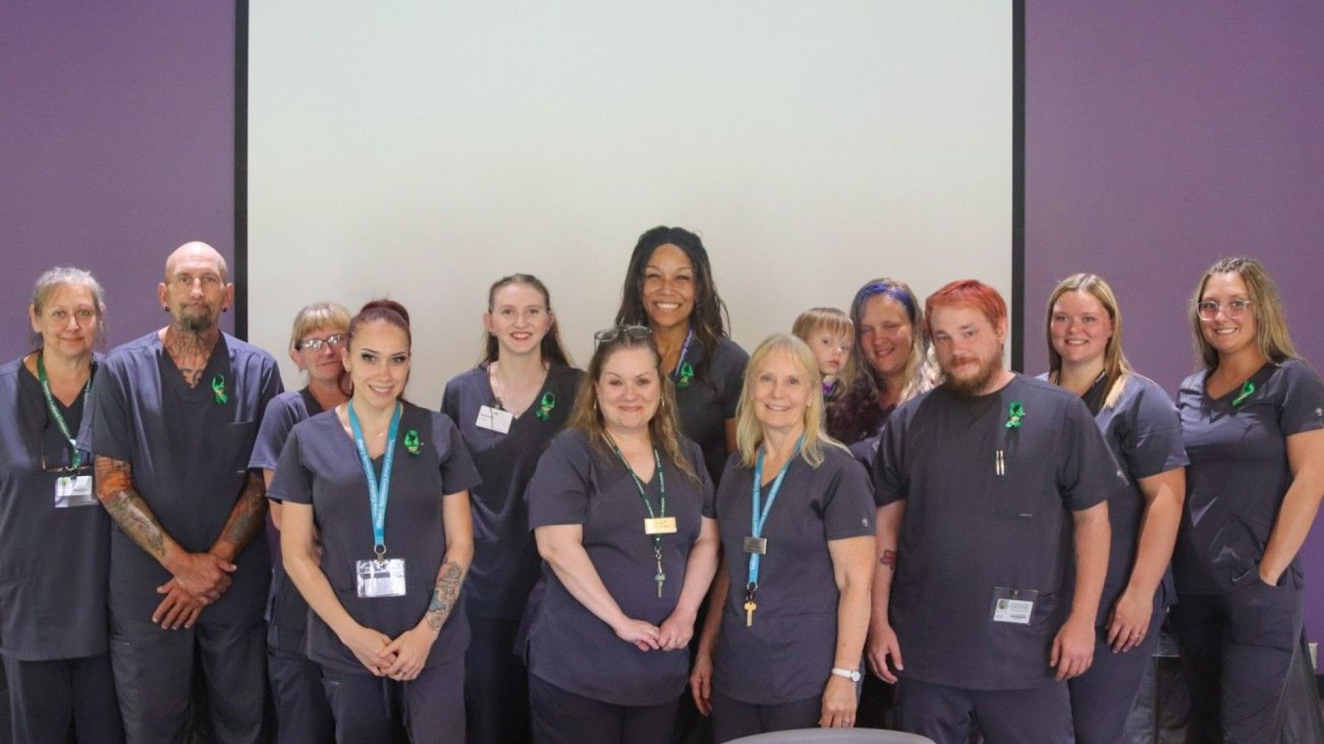 group of 13 individuals in nursing scrubs on stage