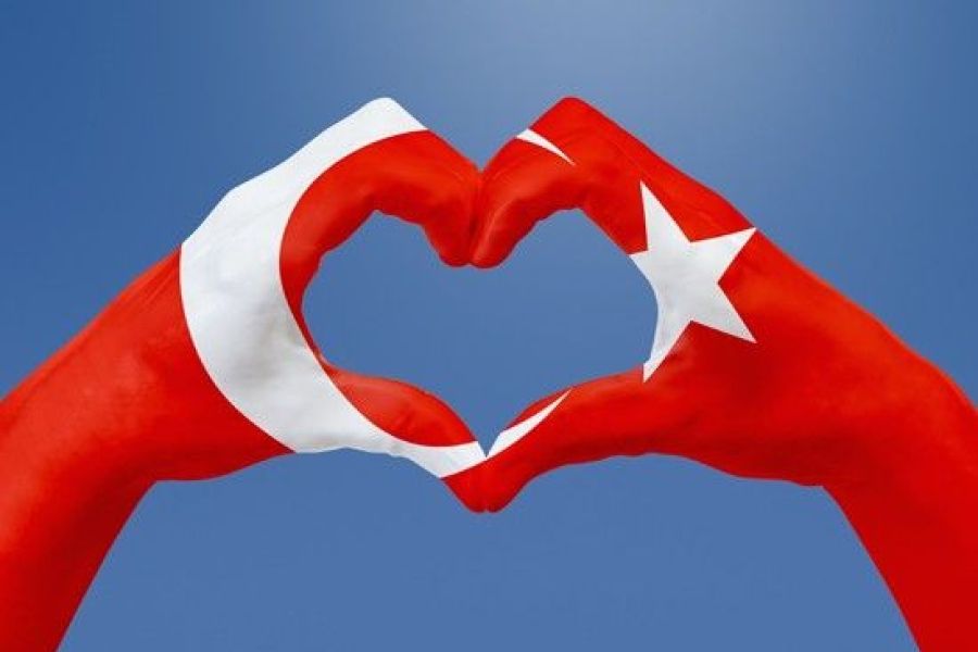 two hands together forming a heart with the coloring of a Turkey flag