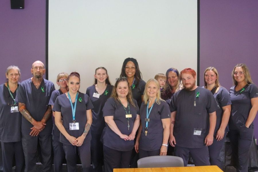 group of 13 individuals in nursing scrubs on stage