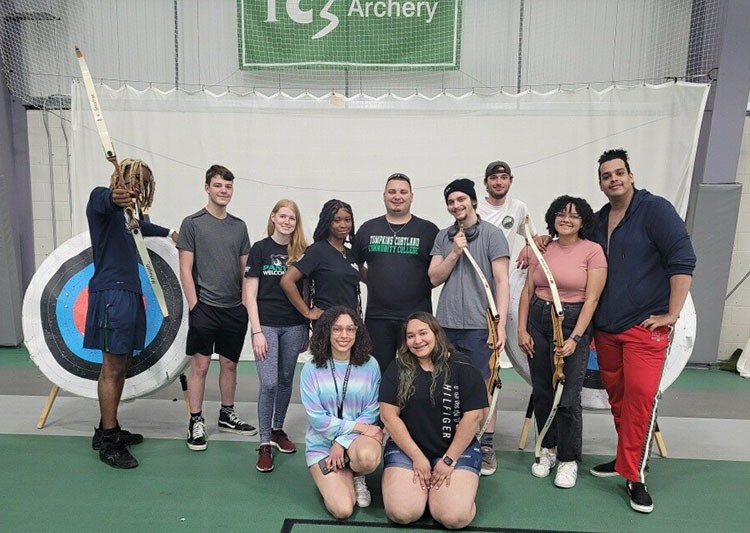 groups of students posing in front of archery targets