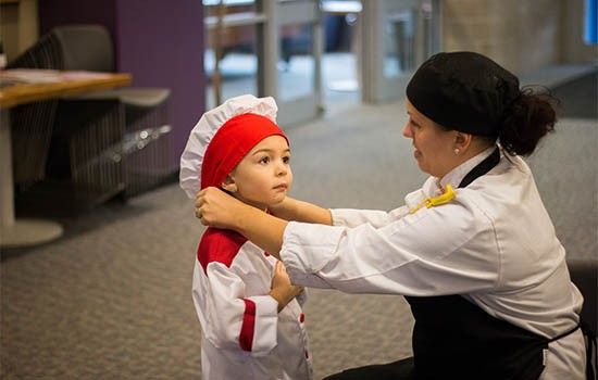 Woman putting chef hat on toddler