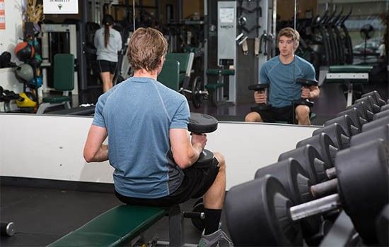 Student sitting on fitness bench with weights