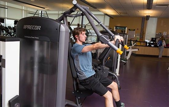 Student using arm lift machine in fitness center